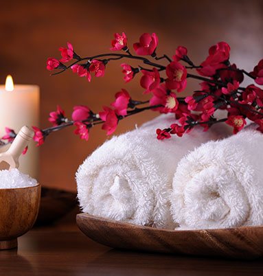 Two white towels with candles and flowers