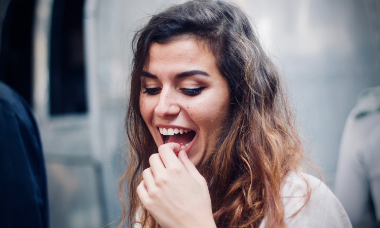 Brunette woman touches a tooth on her lower jaw as if it were loose
