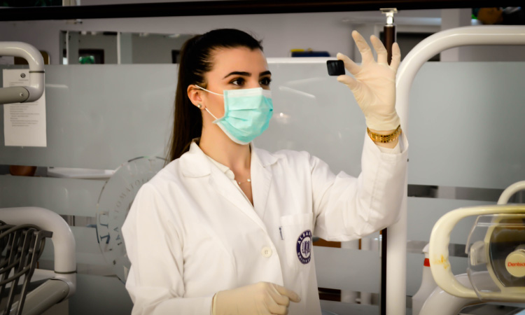 masked dental hygienist looking at an xray