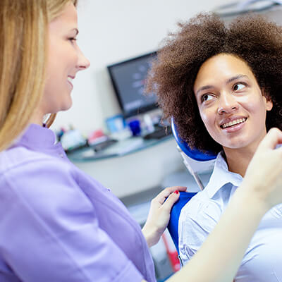 A woman speaking to a dental hygienist before her root canal
