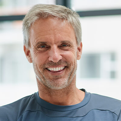 a middle-aged man with a dental crown smiling