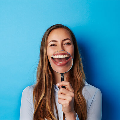 a woman holding a magnifying glass in front of her smile