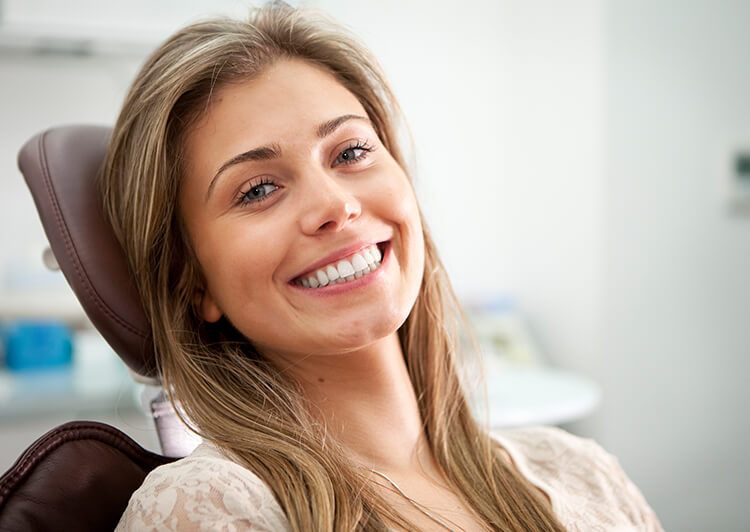 a woman sitting in a dental chair smiling after a successful root canal consult