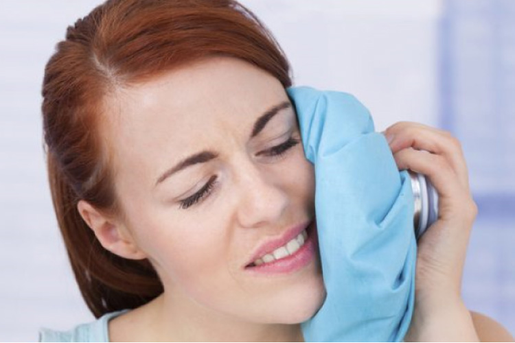 woman using an ice pack to sooth painful wisdom teeth