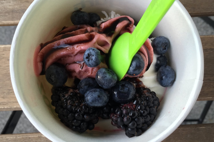 Aerial view of frozen yogurt with fresh berries and a green spoon