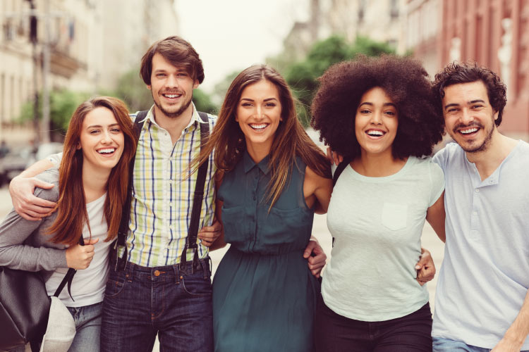 five college students walking arm in arm on campus