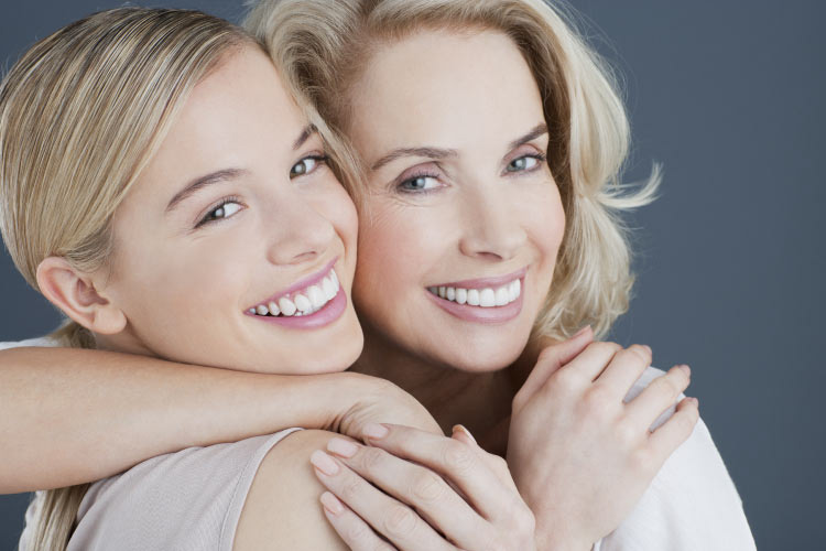 twp blond women hug and smile after getting professional teeth whitening treatments