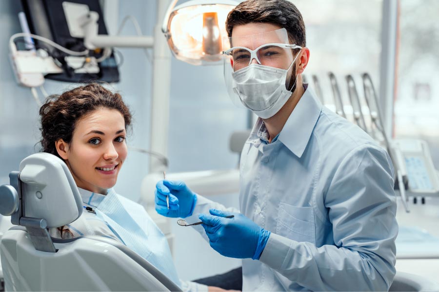 dentist wearing a mask puts a young patient at ease during her dental exam