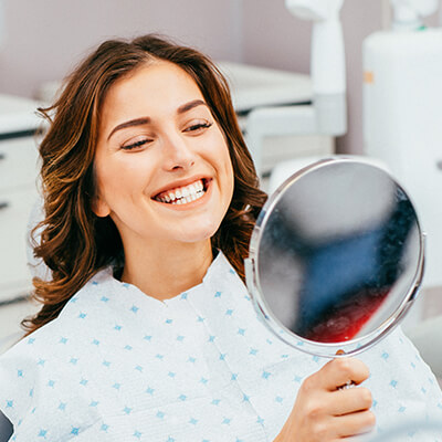 woman examining her bright, white smile in a mirror