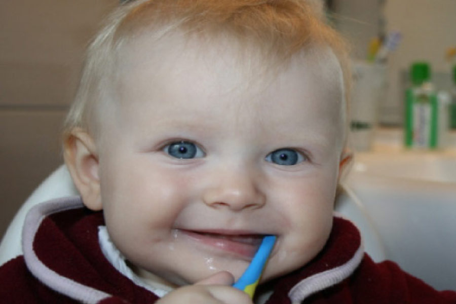 blue eyed baby boy with a tooth brush in his mouth